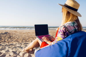 A digital nomad working on her laptop on the beach